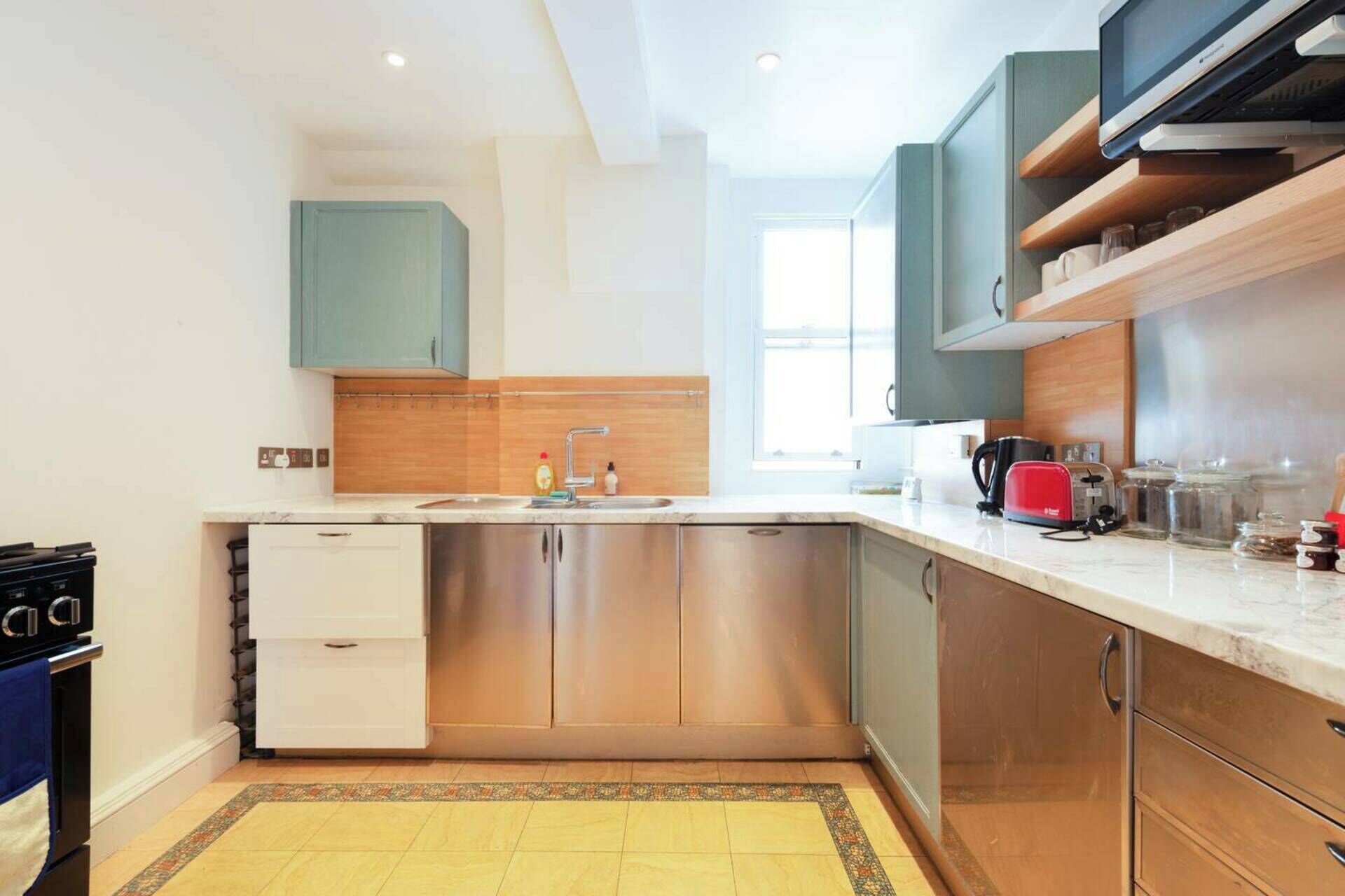 A modern kitchen with stainless steel appliances, a built-in oven, and a window providing natural light.
