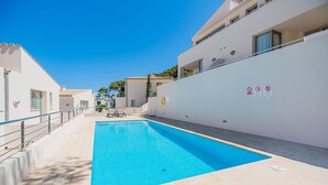 A swimming pool area with a clear blue pool, adjacent buildings, and a no diving sign. - Seaside Escape in Cala Sant Vicenc (Pollença)