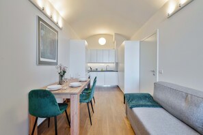 A compact living space with a dining area, kitchenette, and a sofa. - Elegant Apartment Near City Center with Bike Path (Hlavní město Praha)