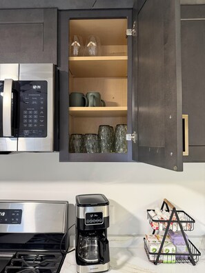 A kitchen with a microwave, a coffee maker, and a shelf with glassware and mugs. - Gorgeous 2-bedroom condo with Rooftop deck in downtown Manchester (Manchester)