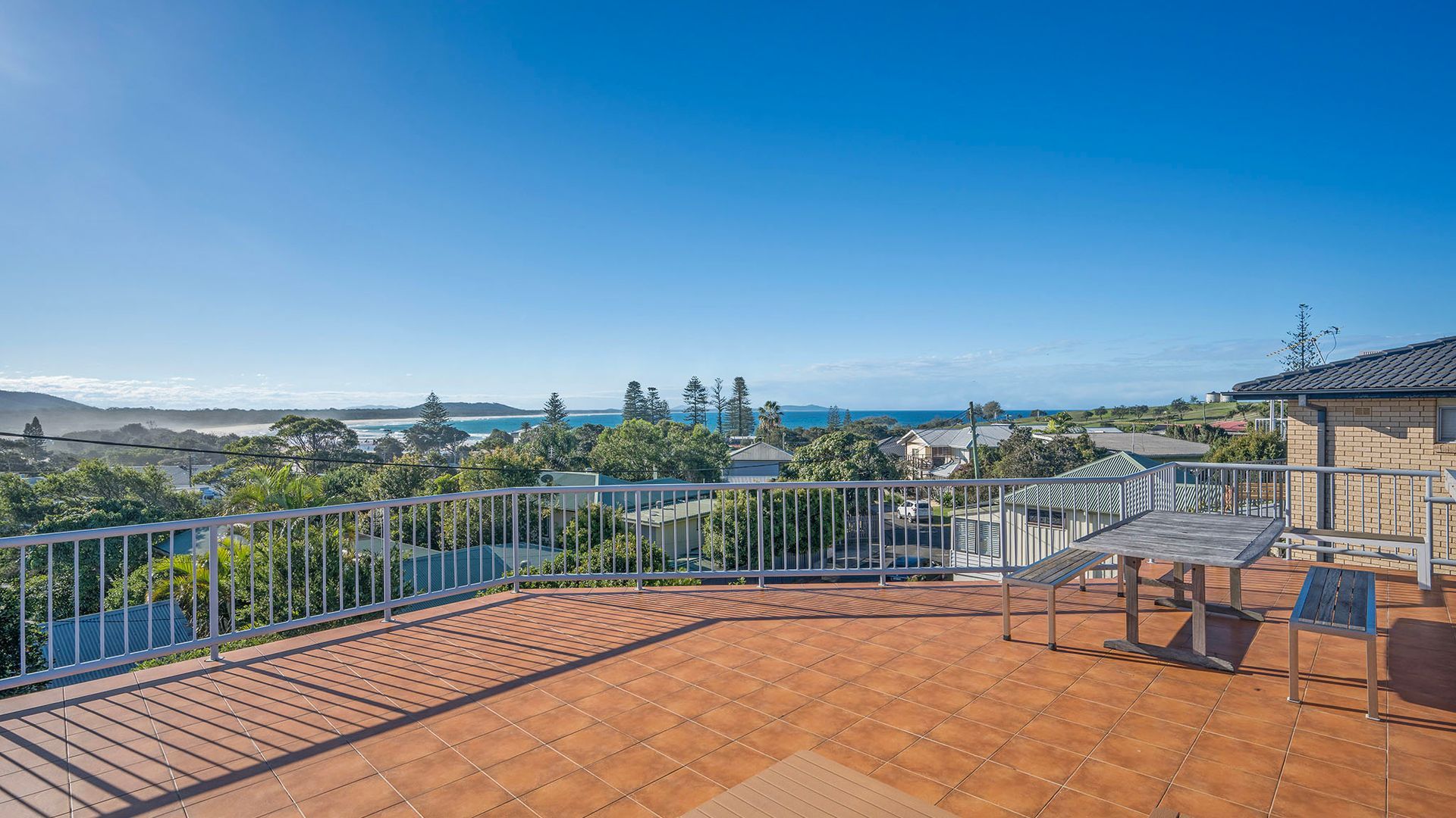 A rooftop terrace with a view of the sea and hills.