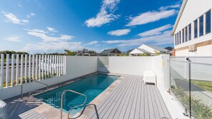 A swimming pool with a wooden deck, surrounded by a white fence, and a clear blue sky above. - Breakwall Retreat - Harrington (Harrington)