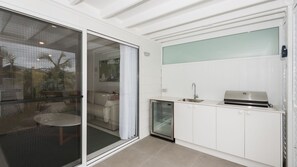 A modern kitchen with a built-in oven, a sink, and a glass door leading to a patio area. - Breakwall Retreat - Harrington (Harrington)