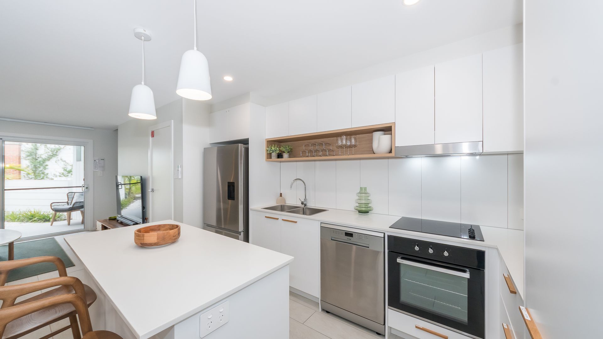 A modern kitchen with white cabinetry, stainless steel appliances, and pendant lighting.