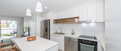 A modern kitchen with white cabinetry, stainless steel appliances, and pendant lighting.