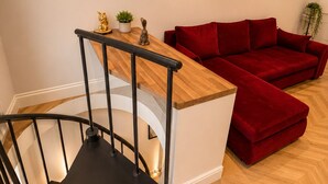 A modern interior with a wooden staircase, a red sofa, and a heart-shaped wall decoration. - Hyde Park Premium Duplex Apartment (London)