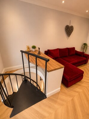 A modern interior with a wooden staircase, a red sofa, and a heart-shaped wall decoration. - Hyde Park Premium Duplex Apartment (London)