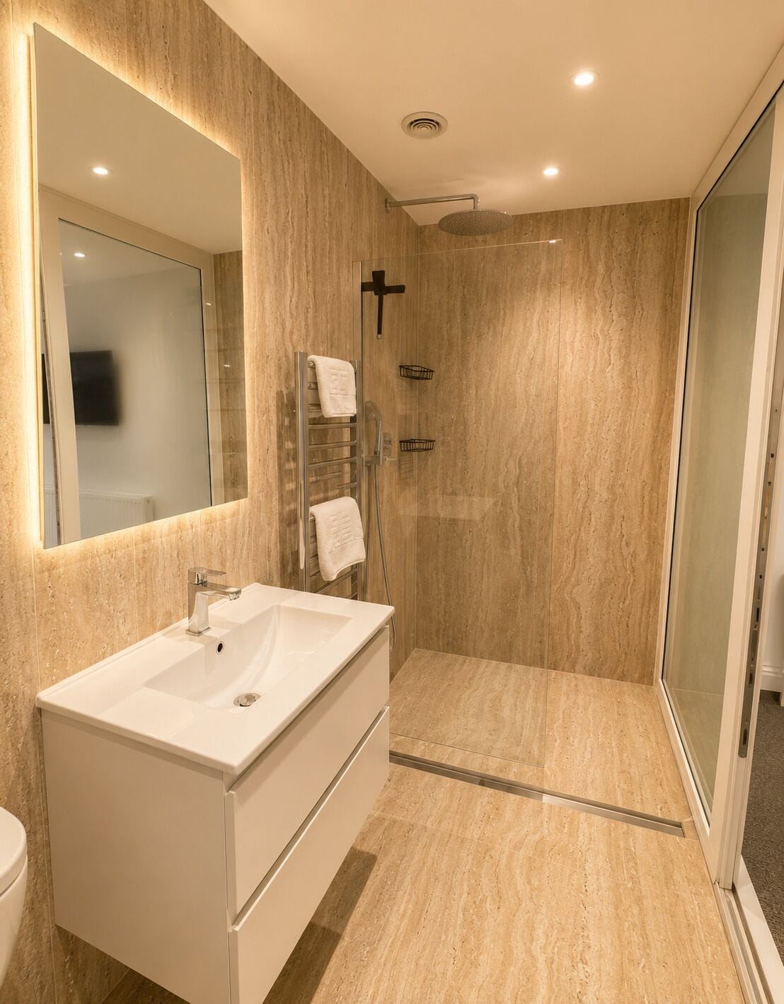 Een moderne badkamer met een grote spiegel, een witte wastafel, een douchecabine van glas en een handdoekhouder.