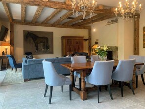 Un comedor con mesa y sillas de madera, un sofá y una araña.