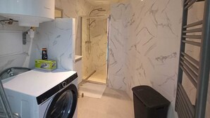 A compact bathroom with a washing machine, a shower, and a towel rack. - Modern Studio in Downtown Roubaix With High Speed Internet and Workspace (Roubaix)