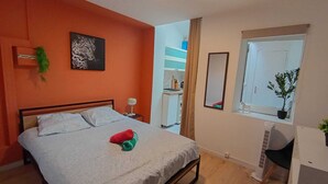 A bedroom with a bed, a nightstand, a mirror, and a window with a plant. - Modern Studio in Downtown Roubaix With High Speed Internet and Workspace (Roubaix)