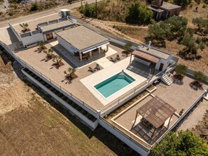 Ein modernes Wohnhaus mit Dachpool, Sitzgelegenheiten im Freien und einer überdachten Terrasse.