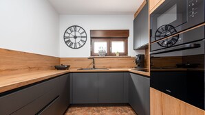 Cocina moderna con armarios oscuros, encimeras de madera y dos relojes de pared.