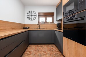 Eine moderne Küche mit dunklen Schränken, Holz Arbeitsplatten und zwei Wanduhren.