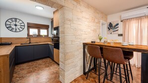 Una cocina moderna con una pared de piedra decorativa, encimera de madera y zona de bar con taburetes.