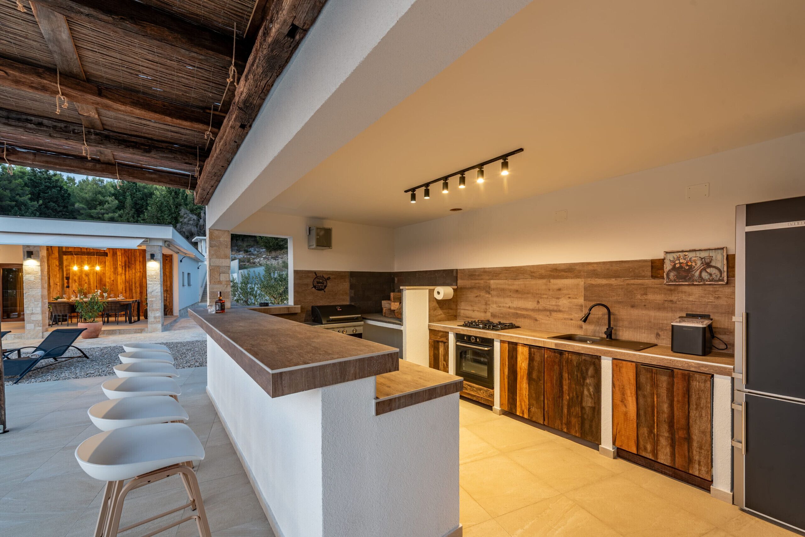 A modern kitchen with a bar area, outdoor seating, and a view of the surrounding landscape.