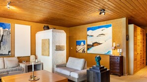 A modern living room with a wooden ceiling, a sofa, a coffee table, and artwork on the walls. - Villa “Mona Lisa” with Mountain Views, Private Terrace, and Wi-Fi (Seefeld)