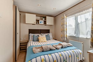 Ein Schlafzimmer mit einem Bett, einem Kleiderschrank, einem Fenster mit Vorhängen und einer Heizung.
