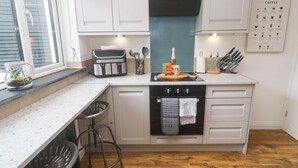 Una cocina compacta con horno integrado, espacio para café y ventana con persianas.