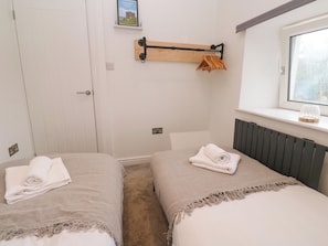 A bedroom with two beds, a window, a radiator, and a towel rack. - The Lookout (Redruth)