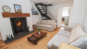 Una sala de estar con chimenea, un sofá, una mesa de centro y una escalera.