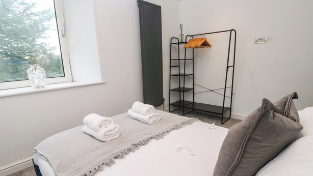 Una cama bien hecha con toallas dobladas, un plaid gris y una almohada gris.