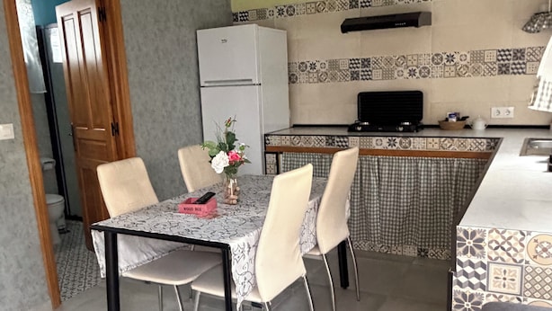 Une cuisine de taille réduite, équipée d’un réfrigérateur, d’une cuisinière et d’un plan de travail recouvert de carreaux.