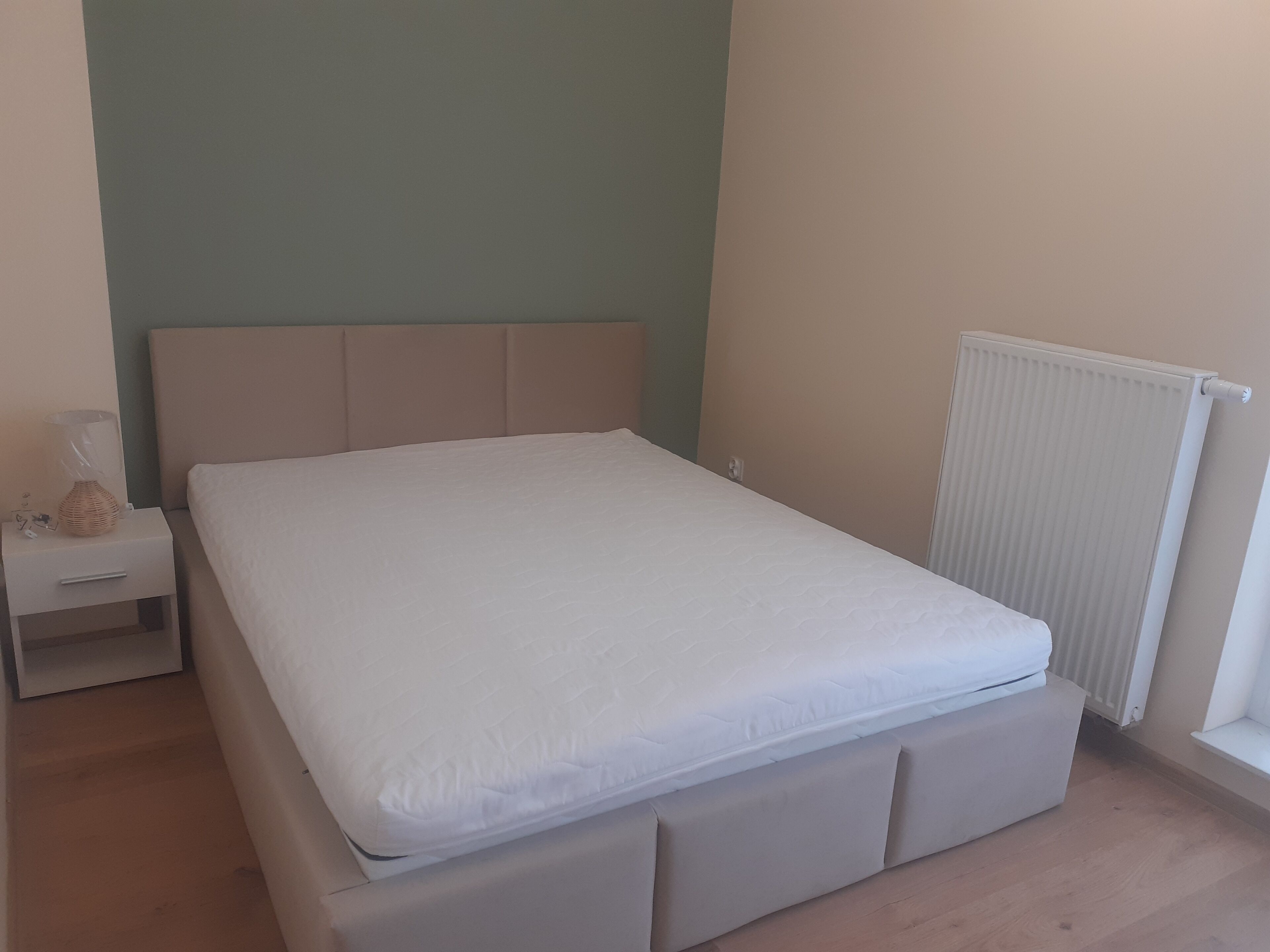 Una camera da letto con un letto, un comodino e un termosifone.