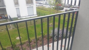 Ein Balkon mit Blick auf einen Parkplatz und ein Gebäude mit weißer Fassade.