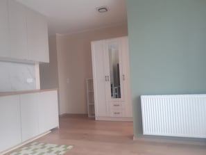 A room with a wooden floor, white cabinets, a radiator, and a green wall. - Beautiful apartment 20 minutes from downtown with parking (Warszawa)