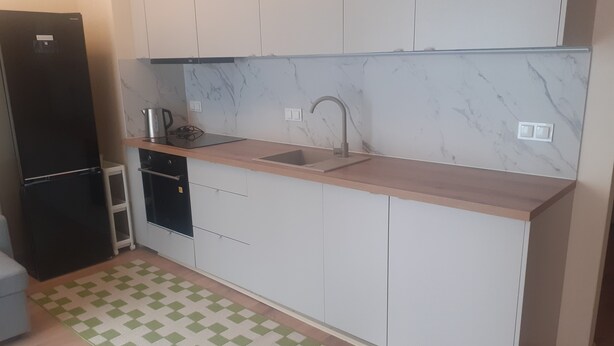 Eine kleine Küche mit Spüle, Arbeitsplatte und einem schwarzen Kühlschrank.