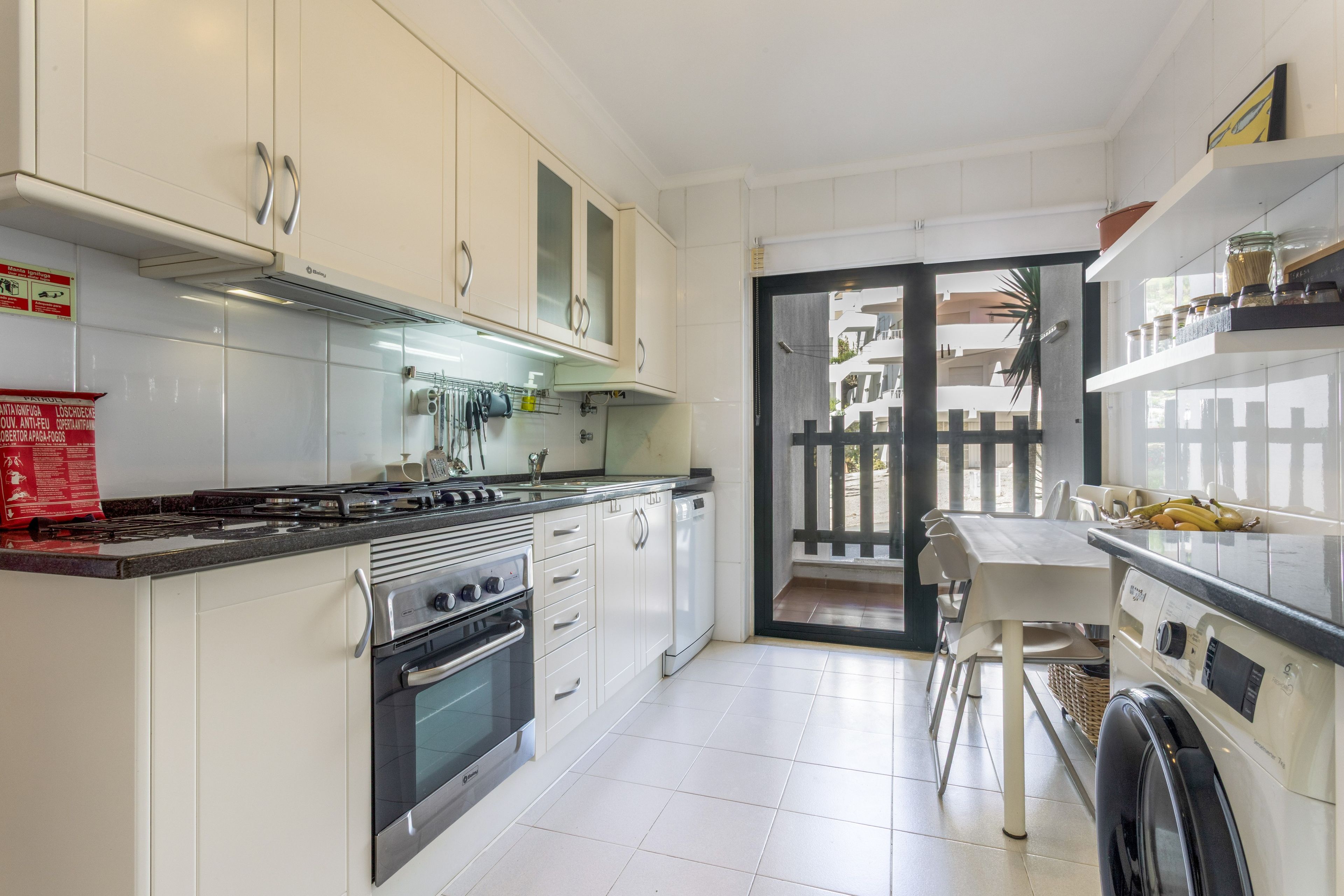 Una cocina moderna con estufa a gas, horno y muebles blancos.