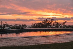 A sunset over a body of water with trees and a lamp post in the foreground. - Hula Hula Ranch - 7 Bedrooms, Pool, Ocean View! (Kamuela)