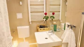 Een badkamer met toilet, wastafel, spiegel, handdoekhouder en douche.