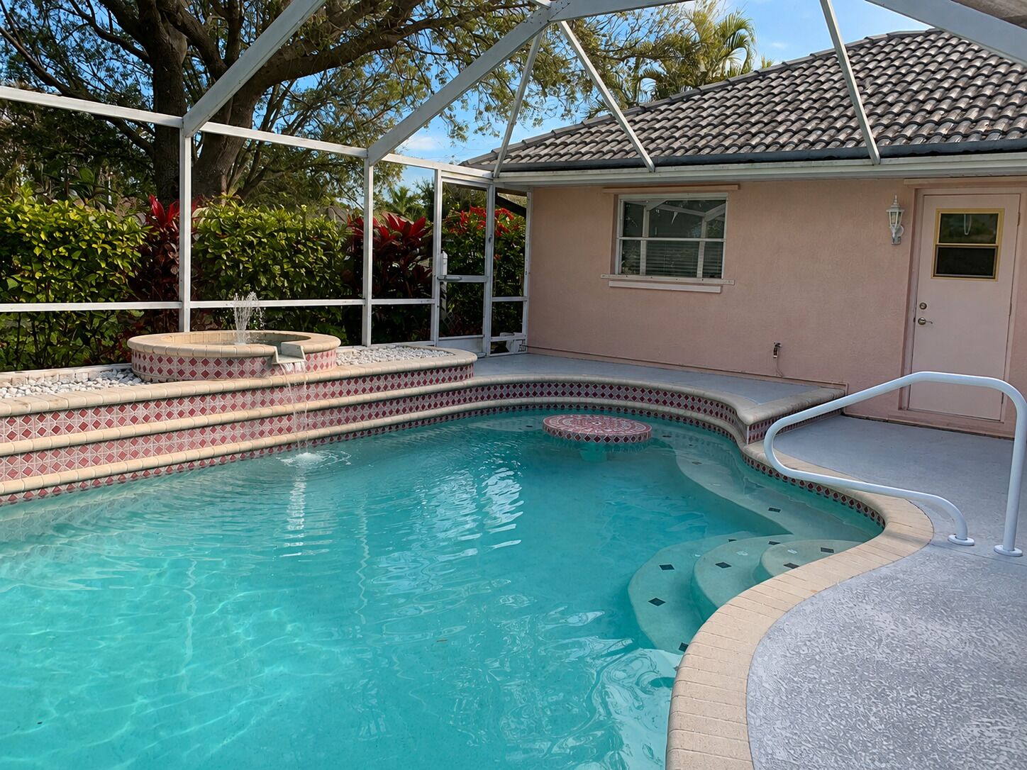 Une piscine dotée d’un jacuzzi intégré, entourée d’une terrasse couverte.