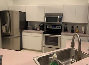 A modern kitchen with stainless steel appliances, including a refrigerator, microwave, and oven.