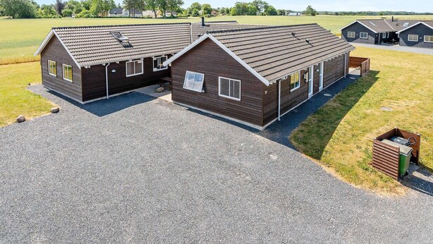 Een tweelaags houten gebouw met een grindpad en een grasveld op de achtergrond.
