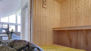 Een sauna met houten wanden, een bank en een schaal stenen.