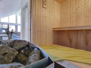 Ein Saunaraum mit Holzwänden, einer Bank und einer Schale mit Steinen.