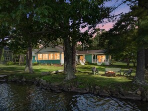 Una casa amb un porxo, un petit jardí i un estany.