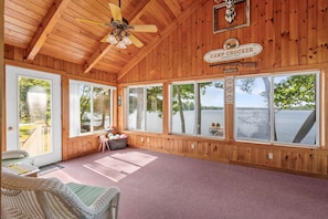 Interior d'una cabana amb finestres grans, un ventilador de sostre i un cartell que diu 'Camp Crocker'.