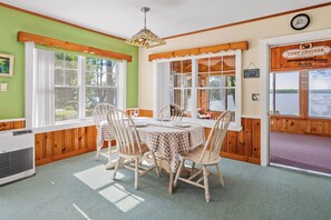 A dining area with a round table, four chairs, and a hanging light fixture. - Camp Crocker Lakefront Home & Dock (Monmouth)