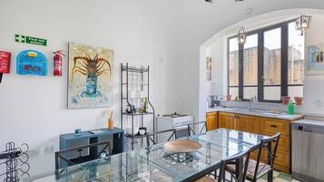Une cuisine moderne avec une table à manger en verre, des meubles de rangement en bois et une vue sur la ville grâce à de grandes fenêtres.