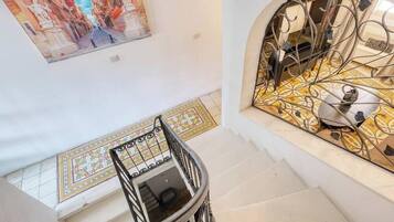 Un escalier avec une rampe en métal, un sol carrelé et un mur orné d’une peinture décorative.