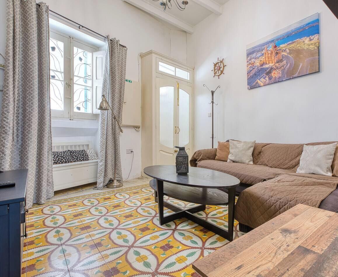 Un salon avec un canapé, une table ronde et un sol à motifs.