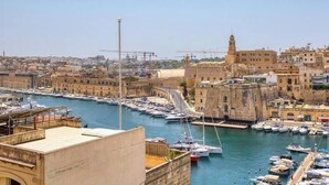 A harbor with boats, a prominent tower, and historic buildings. - Vittoriosa Townhouse 3BR – Rooftop Marina Views (Birgu)