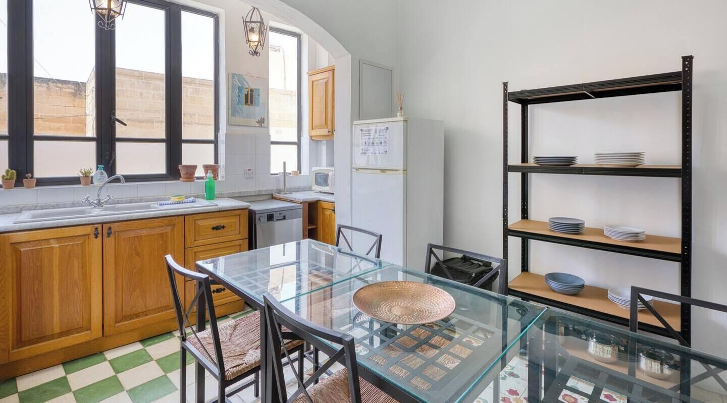 A kitchen with wooden cabinets, a glass table, and a metal shelving unit.