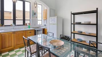 A kitchen with wooden cabinets, a glass table, and a metal shelving unit.