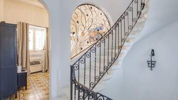 Una escalera con barandales de metal ornamentados y un ventanal con un diseño floral.