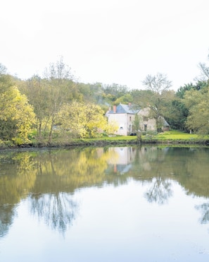 A house by a calm river with a reflection, surrounded by trees and greenery. - Moulin Bondon, in the Berry region on the waterfront; linens provided; pets allowed (Graçay)